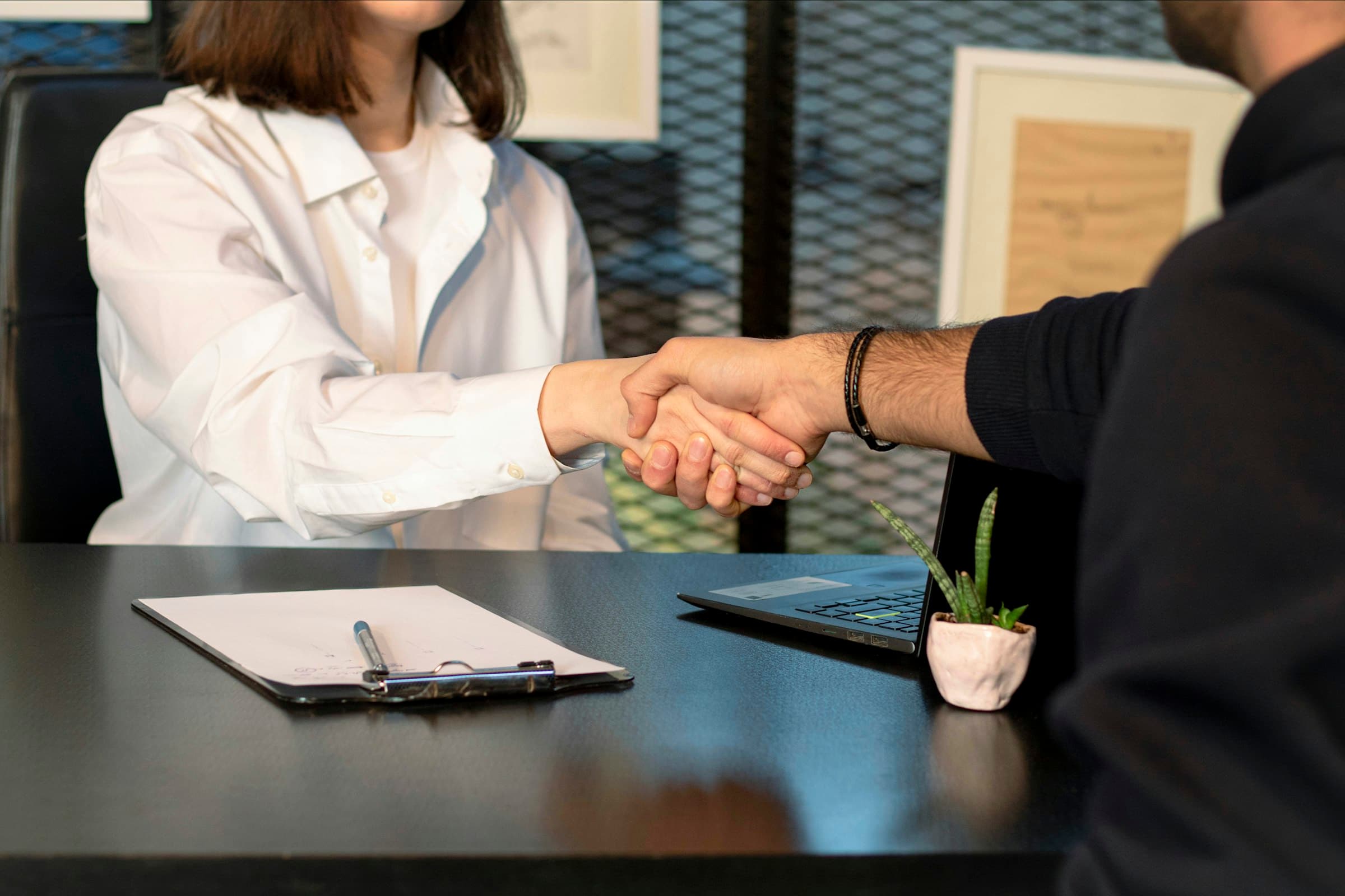 Handschlag zwischen zwei Geschäftspartnern am Schreibtisch